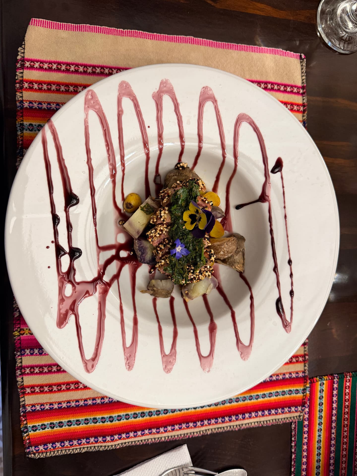 Plated grilled alpaca dish with native potatoes and a zig-zag drizzle of sauce