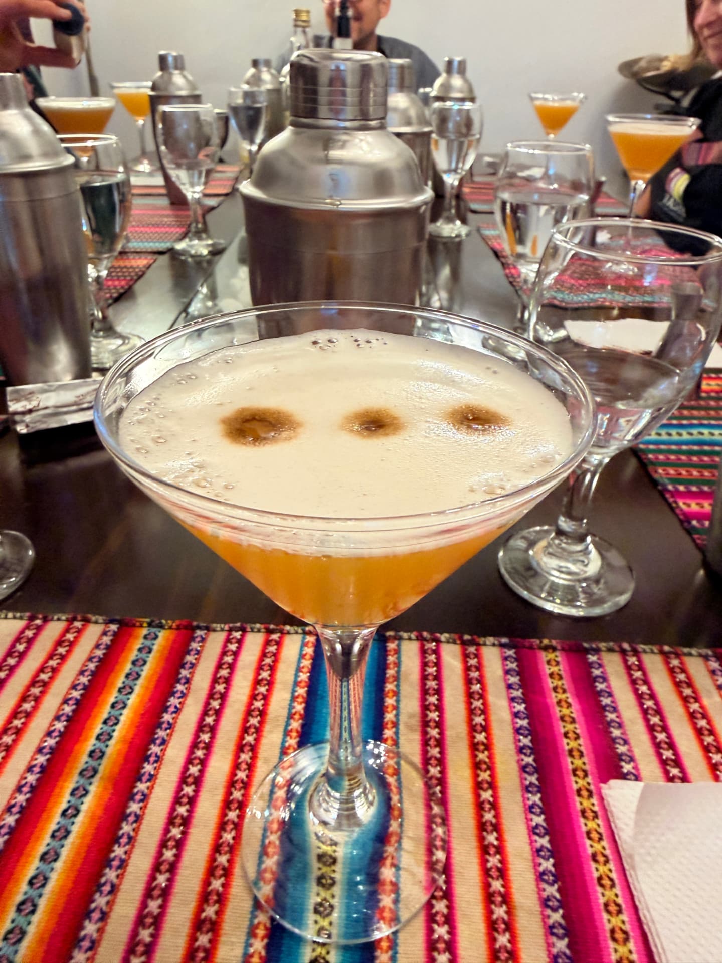 A pisco sour with three drops of angostura bitters on an Andean striped placemat