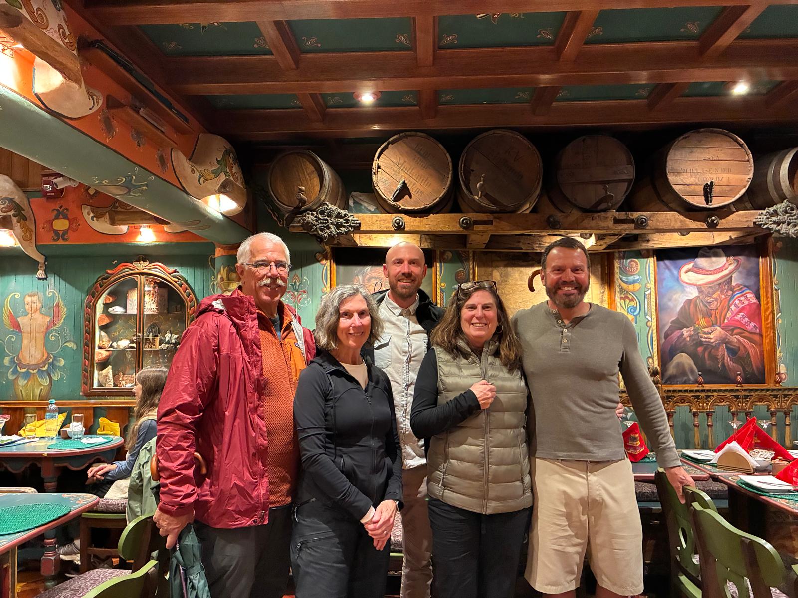 The group posing in a colorful Andean restaurant with painted beams and old wine barrels