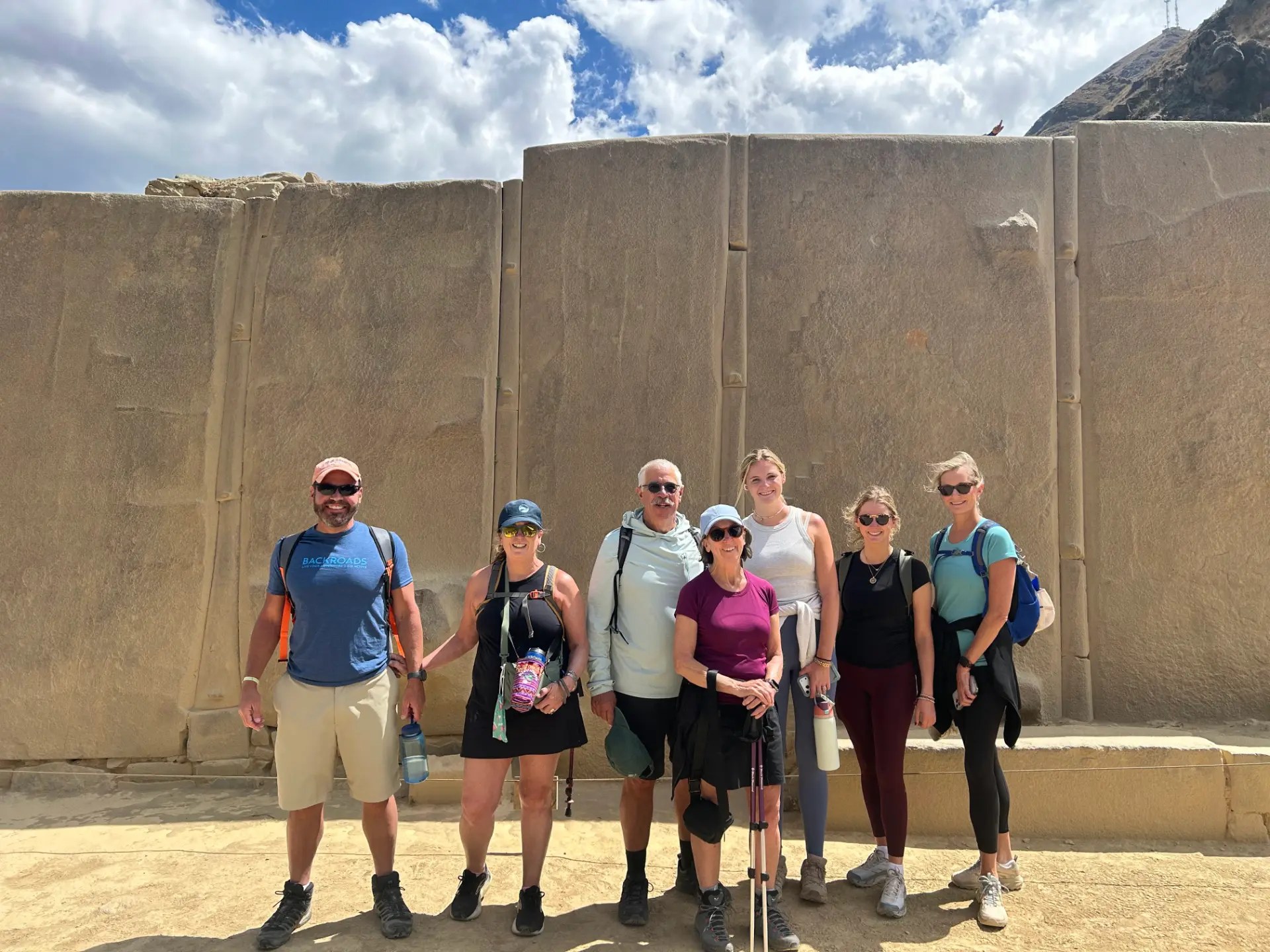 The Backroads group posing in front of the massive granite Wall of the Six Monoliths at Ollantaytambo
